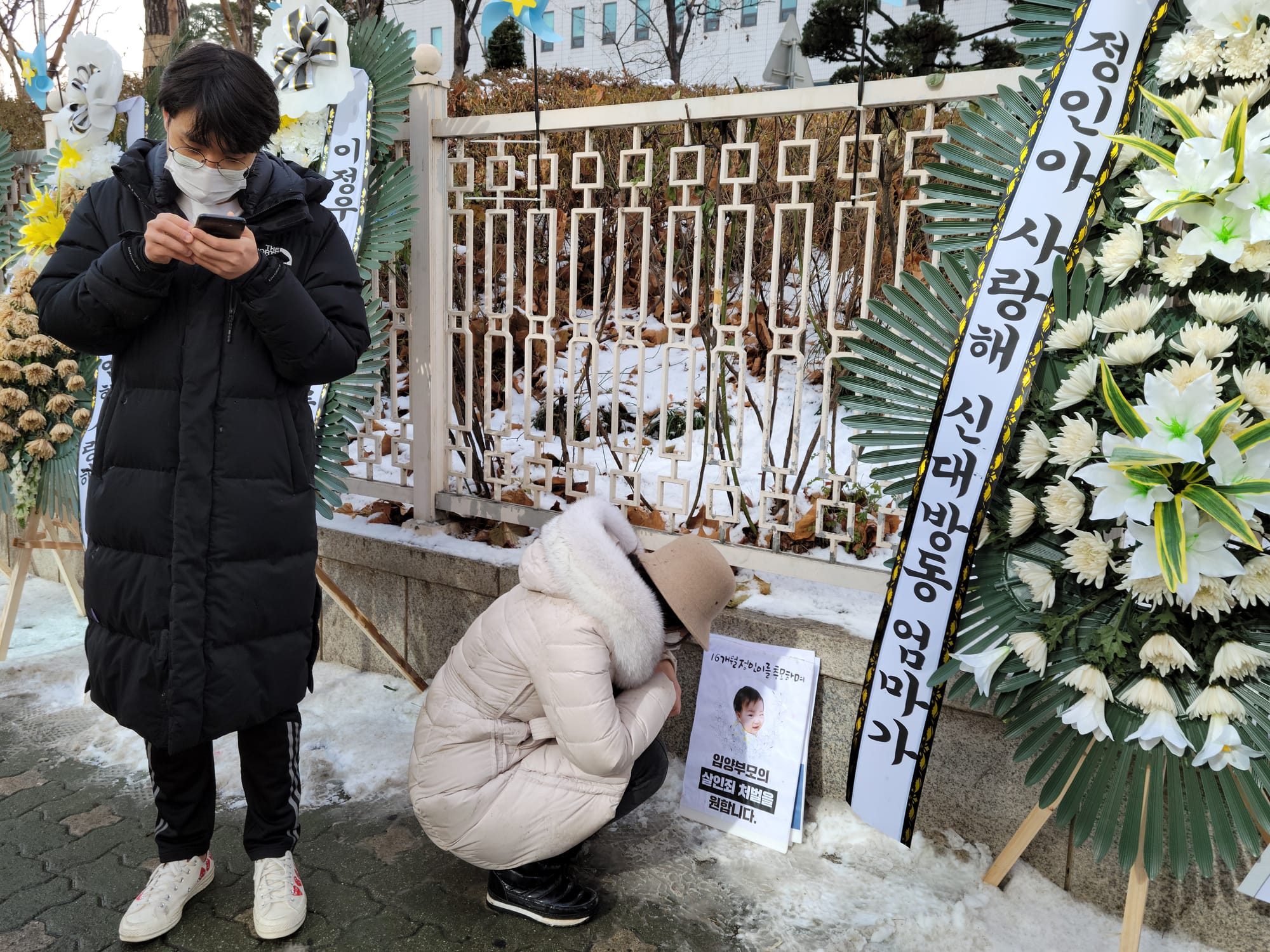 16개월 된 입양 딸 정인 양을 학대해 숨지게 한 혐의를 받는 양부모의 첫 재판이 열린 13일 서울 양천구 남부지방법원에서 재판이 끝난 뒤 한 시민이 법원 청사 앞에 놓인 정인 양의 사진 앞에서 정인 양을 추모하고 있다.