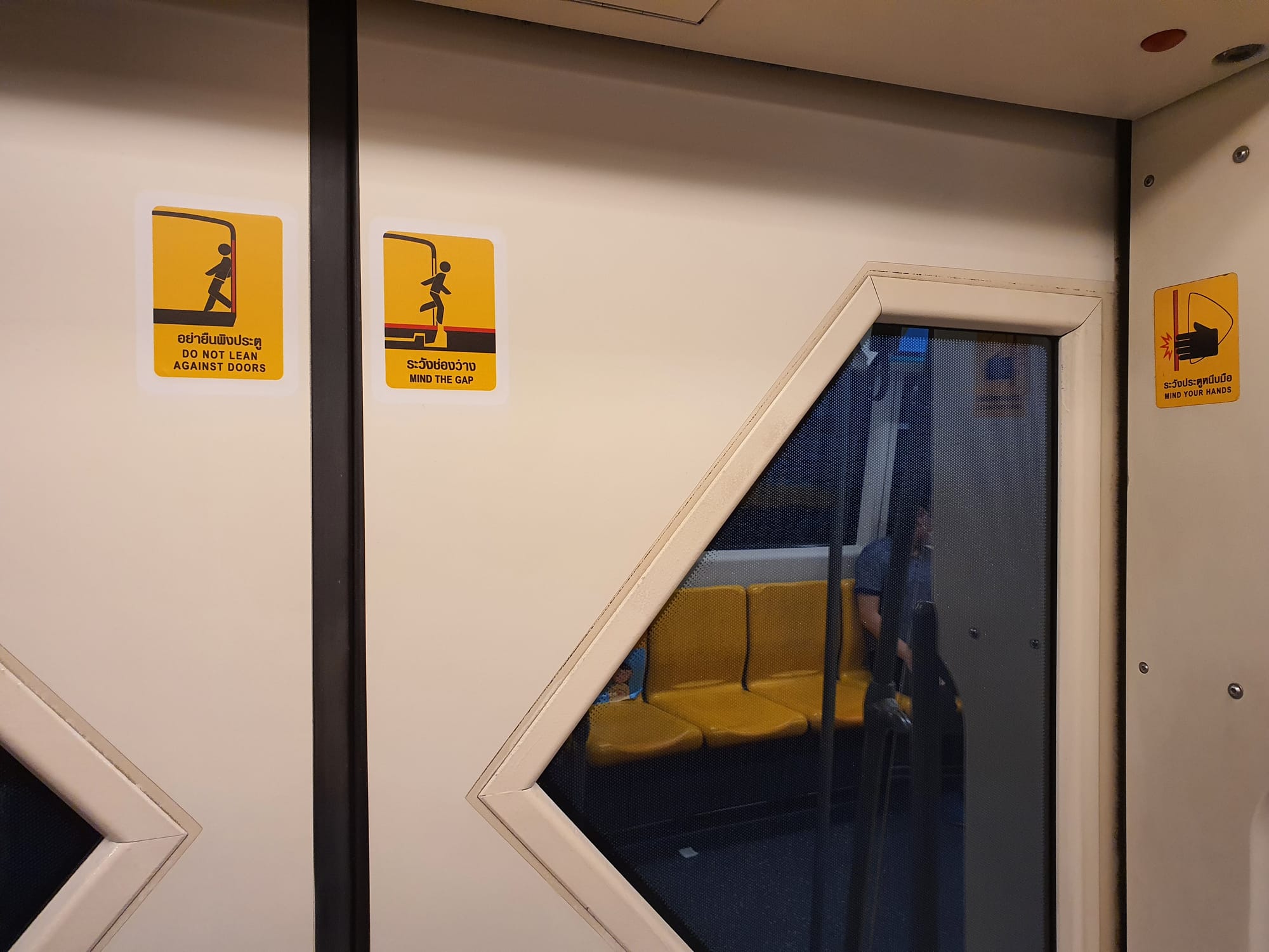 Door safety and "mind the gap" notices on a BTS Skytrain.