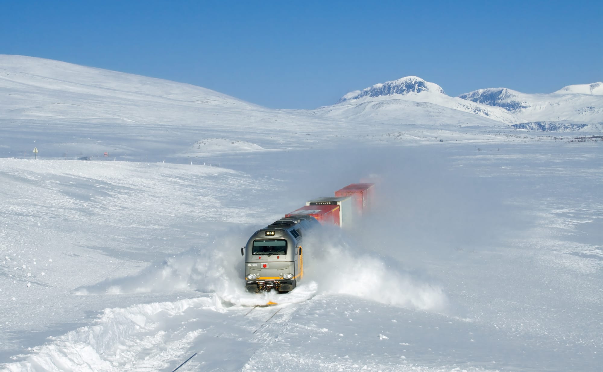 CargoNet Di 12 "Euro 4000" (road number 312 006) plowing through snow drifts at about 100 km/h. The train is an intermodal freight train from Bodø towards Trondheim. The picture was taken on the Saltfjellet between Lønsdal and Bolna, Norway.