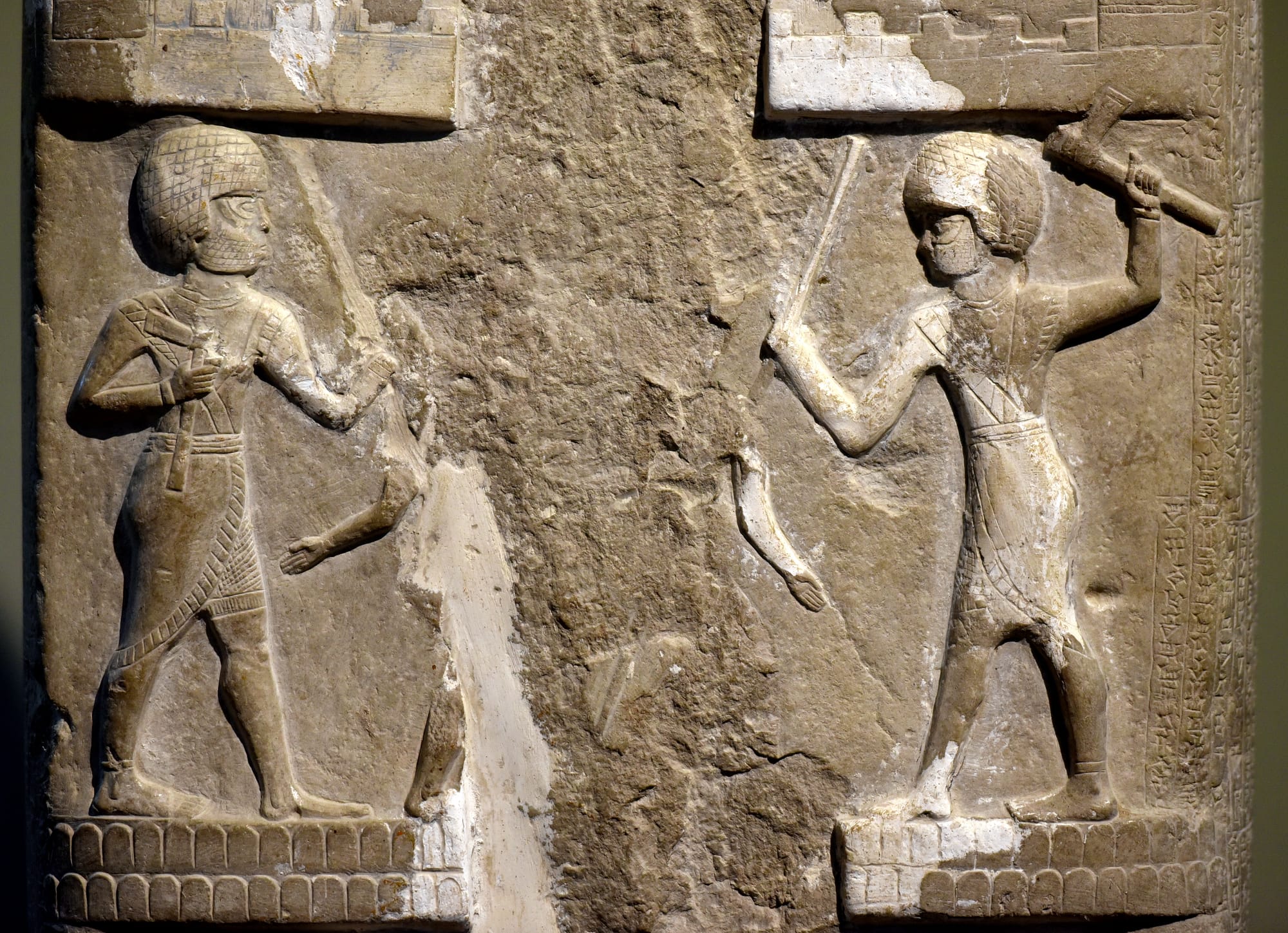 Detail, 2nd register of the stele of Dadusha, king of Eshnunna, c. 1800 BCE. From Eshnunna (modern-day Tell Asmar), in modern-day Diyala Governorate, Iraq. The Iraq Museum in Baghdad, Old-Babylonian Gallery. The second register shows two soldiers with axes attacking two of the enemy. The narrow sides were inscribed with 220 lines of a cuneiform text divided into 17 columns. Dadudha was a king of Eshnunna and this stele commemorates his victory over the city of Qabara in Arbela (modern-day Erbil, in Iraqi Kurdistan) and its king Banu-Ishtar, with the help of king Shamshi-Addu of Ekallatum.