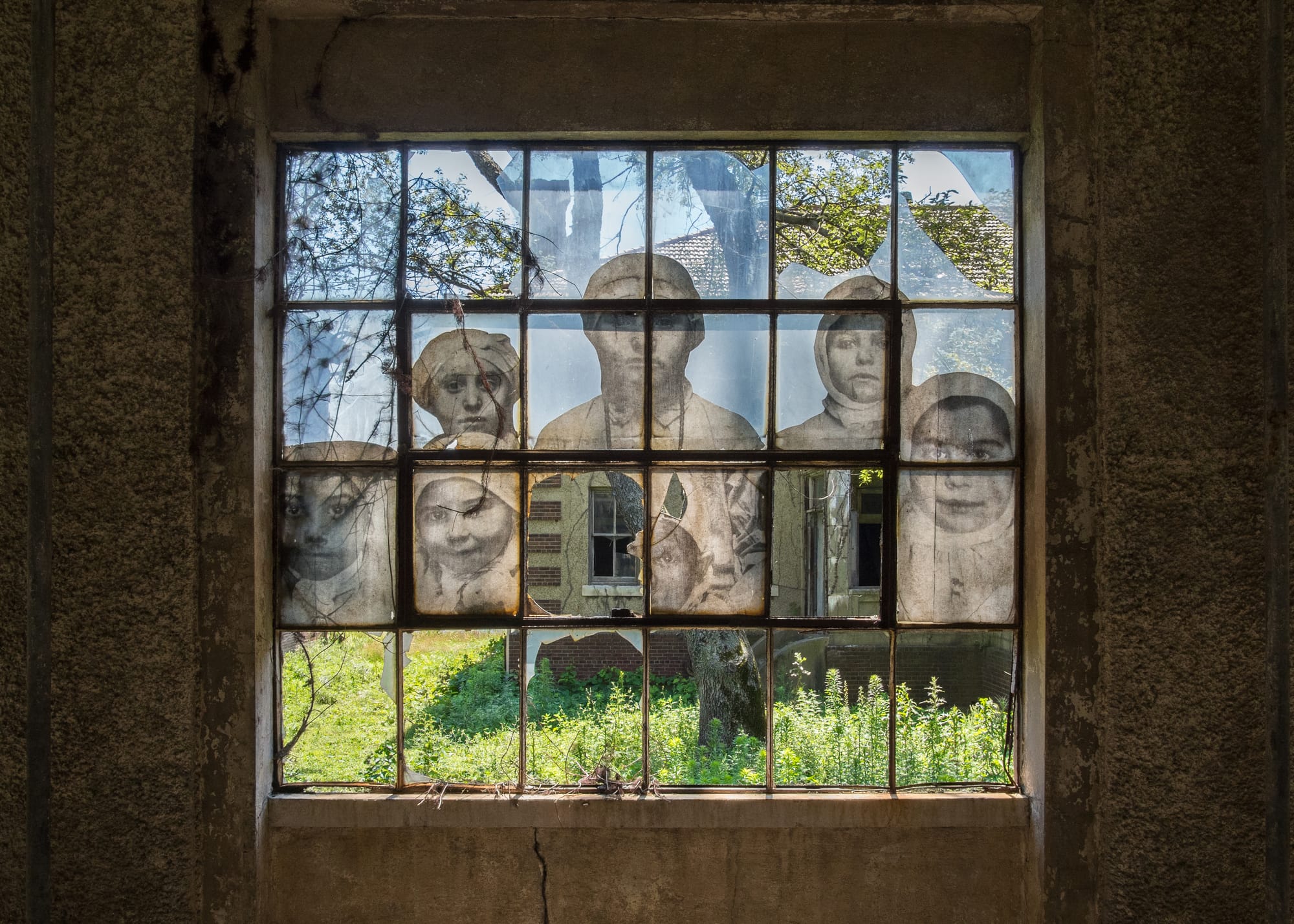 A window in the Ellis Island Immigrant Hospital, closed since 1930. The photograph is one from the early 20th century, when the hospital was operational. In 2014 the French artist JR put up large reproductions of such photographs around the hospital grounds.