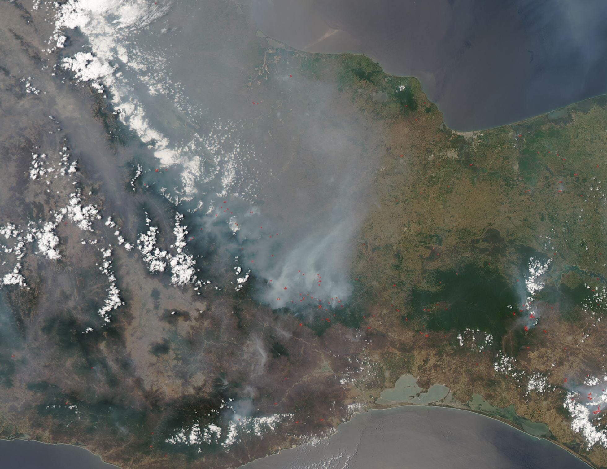 Fires have raged for many weeks in central Mexico, creating so much smoke and haze that on May 11, 2019, authorities declared emergencies in 11 municipalities in the state of Oaxaca. By May 14, Mexico City authorities declared an environmental emergency in the city as smoke caused air pollution to reach levels well above what the World Health Organization (WHO) considers safe. WHO recognizes particulate matter (PM2.5) levels of below 25 micrograms per cubic meter of air as safe. The measuring station in Nezahualcoyotl (a city near the northeast corner of Mexico City) recorded PM2.5 levels of 158 micrograms per cubic meter at 5 a.m. on May 14.
Hot, dry temperatures have fueled more than 23 active forest fires in the state of Guerrero (south of Mexico City) alone. The fires have been difficult to control because of strong winds.
March to May is the height of fire season in many parts of the Mexico. Fires have been burning this week in Oaxaca, where more than 7,000 hectares (17,000 acres) of land have been consumed by fires this year.
The Comisión Nacional Forestal has recorded nearly 4,000 fires across Mexico this year, according to a news report on May 7. Another news report on May 14 stated the Comisión said that more than 100,000 acres had been burned across Mexico as of the end of March. Many regions of Mexico may soon get some relief as the rainy season begins in late May or June.
The Moderate Resolution Imaging Spectroradiometer (MODIS) on board NASA’s Aqua satellite acquired a true-color image of the vast smoke across Mexico on May 12, 2019.