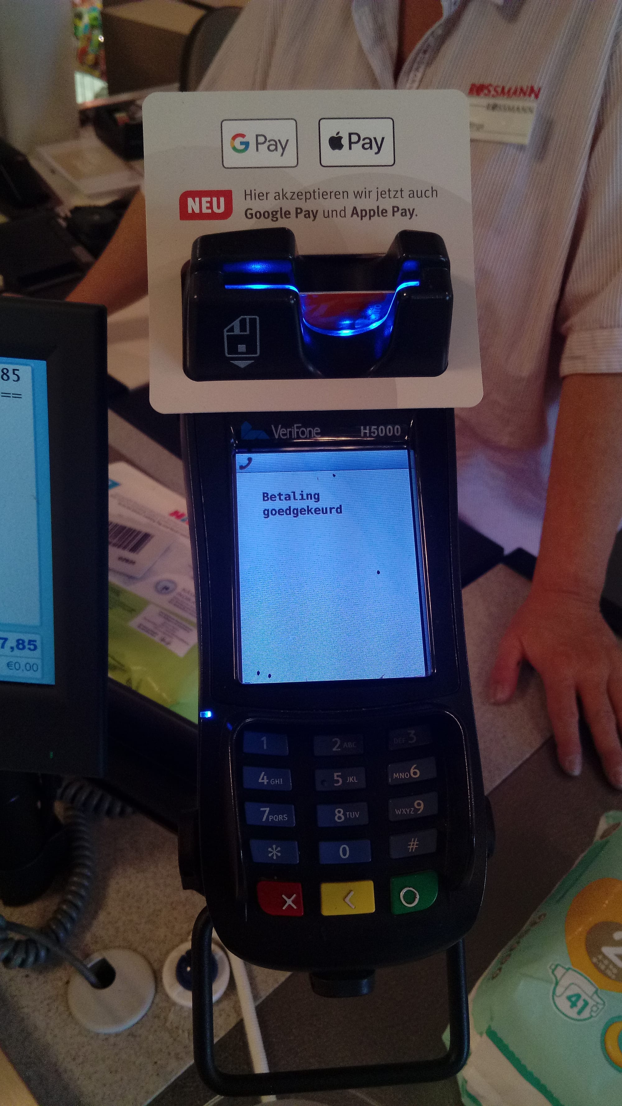A VeriFone H5000 being used while the option to pay with Google Pay and Apple Pay is advertised as "NEU" ("NEW") inside of a Rossmann shop in the East-Frisian village of Bunde, Lower-Saxony.