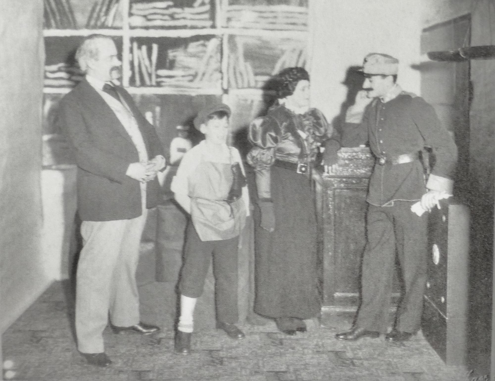 Relatives of the entrepreneur Julius Schindler (1878–1941) of Hamburg during a partially costumed rehearsal for a private stage play on the occassion of the 25th anniversary of Schindler's marriage with Irma Schindler, nee Spitzer (1883–1954). The couple married on April 2, 1905. The idea for this stage play may have been developed by Fritz Schindler (1920–2016) since he at that time attended the reform boarding school Schule am Meer of principal Martin Luserke on the island of Juist where stage play was a major subject. From the left: Gerhard „Harry“ Spitzer, acting as the late father Hermann Spitzer (1850–1917) of Irma Schindler. Fritz Schindler acting as a shoemaker's apprentice to represent Hermann Spitzer's leather business, Anni Schindler (1906–1999) acting as her mother Irma and Gustav Schindler (1910–1988) acting as his father Julius during courtship wearing a Austrian-Hungarian uniform.
