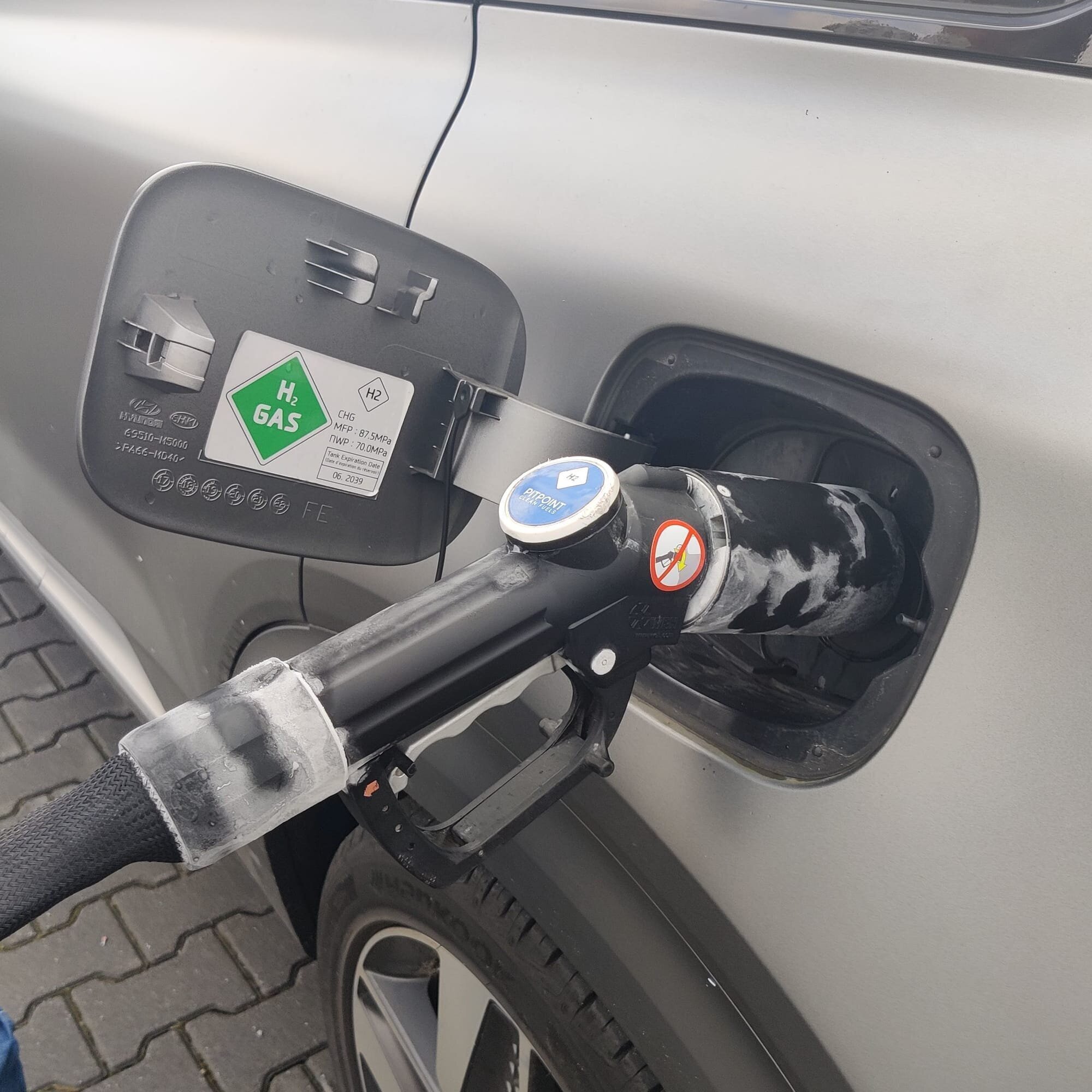 The refueling of a Hydrogen-powered vehicle. The vehicle is a Hyundai Nexo.
Note the condensation around the handle; this is because of the hydrogen gas expanding causing the handle to freeze.