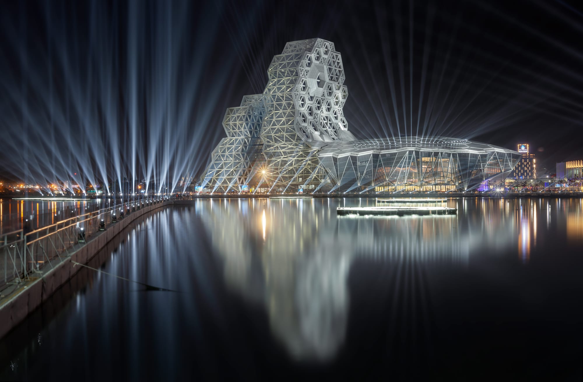 The northeast side of the Kaohsiung Music Center during the 2022 Taiwan Lantern Festival. The temporary floating bridge "Great Tiger Bridge" on the left side was specially built for the festival.
This image is a blend of different exposure combinations:

For architectures: 1.3" f/11 ISO 100; 1.6" f/11 ISO 100; 5.0" f/11 ISO 100; 10.0" f/11 ISO 100; 20.0" f/11 ISO 100
For light beams and reflection: 59.0" f/25 ISO 100; 119.0" f/25 ISO 100