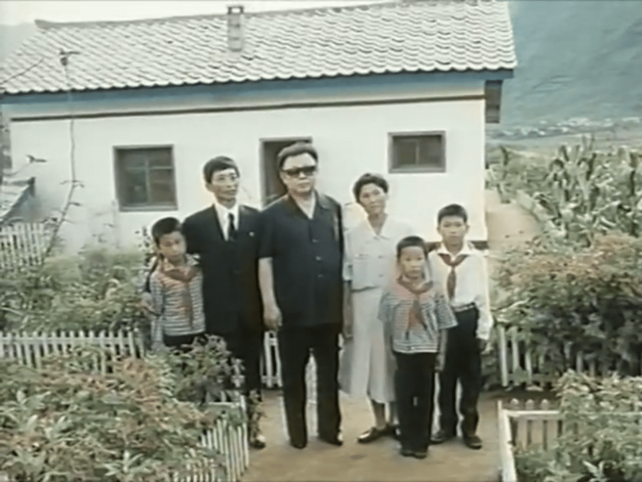 Kim Jong-il with a local family in a propaganda photo during the 1995-1999 famine.