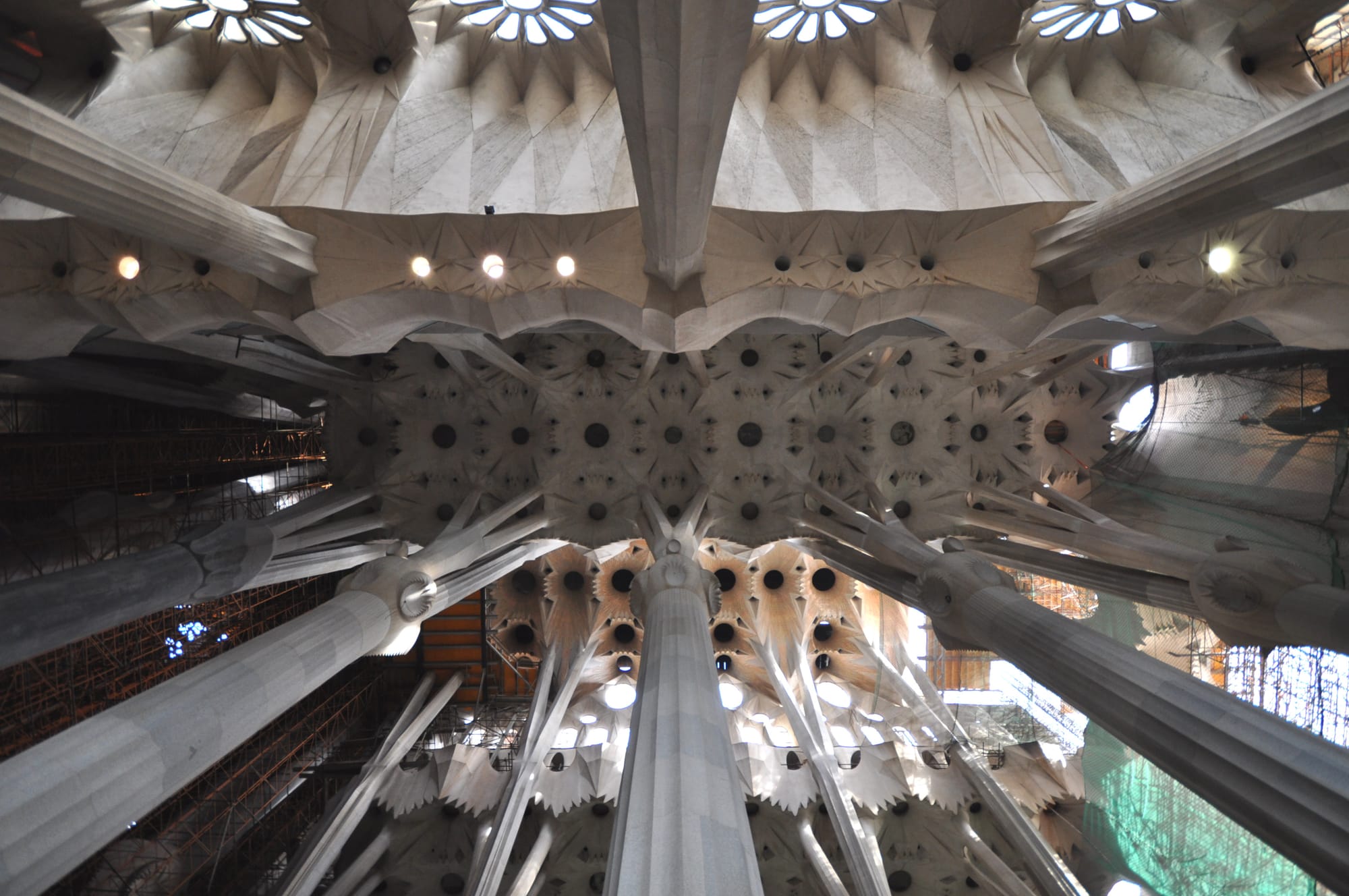 The church plan is that of a Latin cross with five aisles. The central nave vaults reach 45 meters while the side nave vaults reach 30 meters. The transept has 3 aisles. The columns are on a 7.5 meter grid however the columns of the apse, resting on del Villar's foundation, do not adhere to the grid, requiring a section of columns of the ambulatory to transition to the grid thus creating a horseshoe pattern to the layout of those columns. The crossing rests on the four central columns of porphyry supporting a great hyperboloid surrounded by two rings of 12 hyperboloids (currently under construction). The central vault reaches 60 meters. The apse will be capped by a hyperboloid vault reaching 75 meters. Gaudi intended that a visitor standing at the main entrance be able to see the vaults of the nave, crossing, and apse, thus the graduated increase in vault loftiness. The columns of the interior are a unique Gaudi design. Besides branching to support their load, their ever-changing surfaces are the result of the intersection of various geometric forms. The simplest example is that of a square base evolving into an octagon as the column rises, then a 16-sided form, and eventually to a circle. This effect is the result of a three-dimensional intersection of helicoidal columns (for example a square cross-section column twisting clockwise and a similar one twisting counter-clockwise).