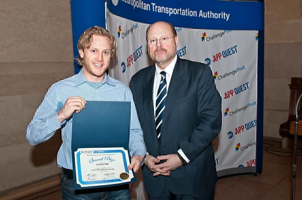 On Feb. 2, 2012, MTA Chairman Joseph J. Lhota (right) announced the winners of the MTA App Quest competition, which sought the best apps for transit riders. Jordan Hill, left, designed Free NYC Subway Locator, which won Second Prize. The app, available for Apple iOS devices, automatically calculates the nearest subway entrances to your current location and lists them by direction, in order of proximity by feet. The app also shows the individual station entrance locations, service alerts, and elevator and escalator outages, all using data provided by the MTA. Photo by Metropolitan Transportation Authority / Patrick Cashin.