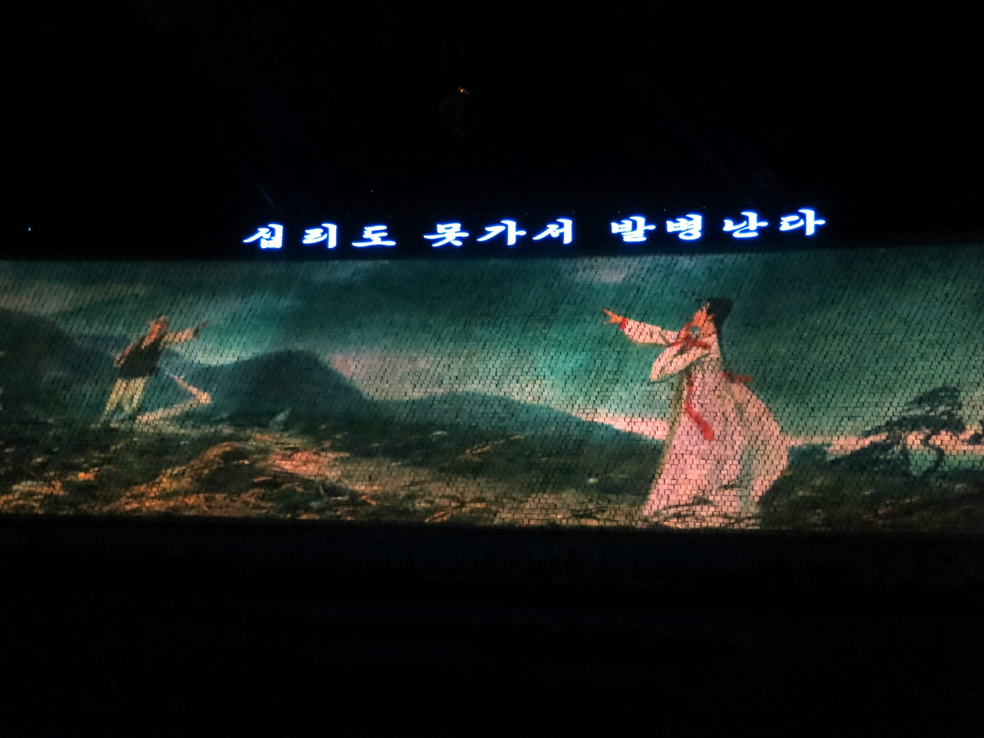 A scene from the folk song "Arirang" at the Arirang Mass Games in Pyongyang, North Korea. The lyrics read: "십리도 못가서 발병난다" (Shall not walk even ten li before his/her feet hurt.)
한국어:  "십리도 못가서 발병난다"