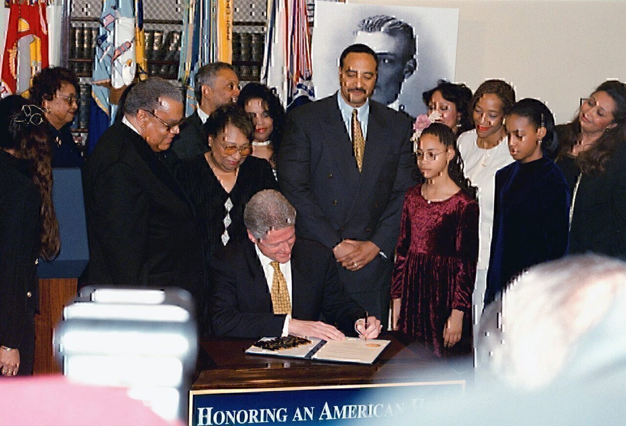 US President William Jefferson Clinton (center) is surrounded by the family members of US Army First Lieutenant (1LT), Henry O. Flipper, the first African American to graduate from the US Military Academy at West Point, as the President signs a document pardoning 1LT Flipper for a 1882 Army conviction for conduct unbecoming an officer and a gentleman. The dishonorable discharge accompanying the conviction had been changed to honorable in 1976.