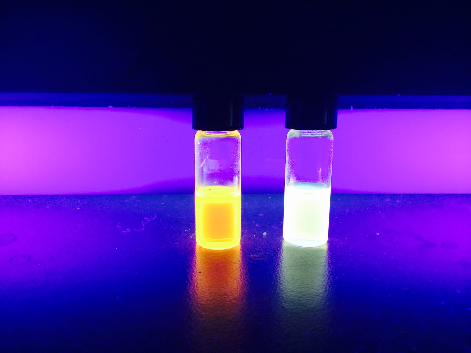 Quantum dot solutions emitting yellow-orange and light-blue light, excited by UV light (manufactured at California Polytechnic San Luis Obispo)