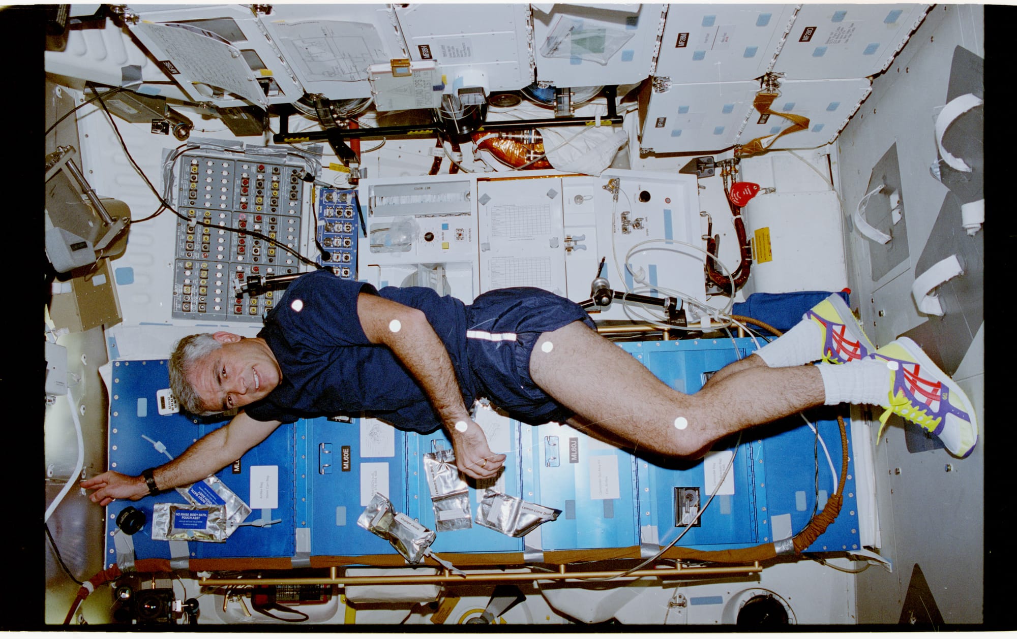 The original finding aid described this as: Description: View of Mission Specialist (MS) Michael R. (Rick) Clifford, in the middeck (MDDK), showing the 6 circular white body monitoring attachment points on his left side: shoulder, arm, wrist, hip, knee and ankle. Clifford is standing in front of the MDDK accommodations rack. Subject Terms: STS-53, DISCOVERY (ORBITER), ASTRONAUTS, MIDDECK, FOOT RESTRAINTS LIFE SCIENCES, ONBOARD ACTIVITIES Categories: Crew Activities Interior_Exterior: Interior Ground_Orbit: On-orbit Element: Shuttle Middeck Original: Film - 35MM CN Preservation File Format: TIFF