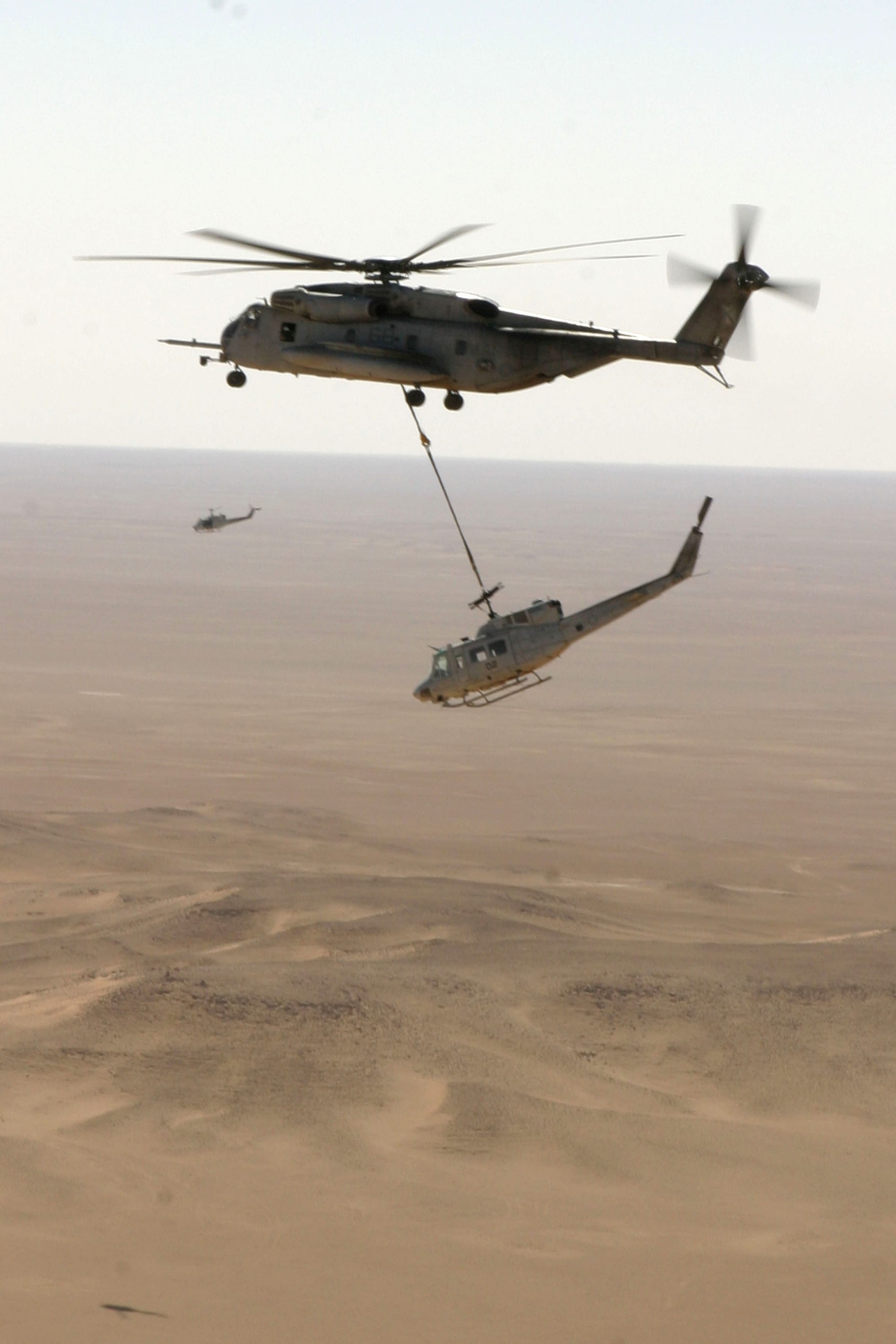 Iraq (Oct. 25, 2005) - A U.S. Marine Corps CH-53 Super Stallion helicopter, assigned to Marine Heavy Helicopter Squadron Four Six Six (HMH-466), externally lifts a UH-1N Huey over Iraq. The CH-53 picked-up the UH-1N Huey from Al Qaim, Iraq and will fly it to Al Asad, Iraq for repairs. U.S. Marine Corps photo by Cpl. James P. Aguilar (RELEASED)