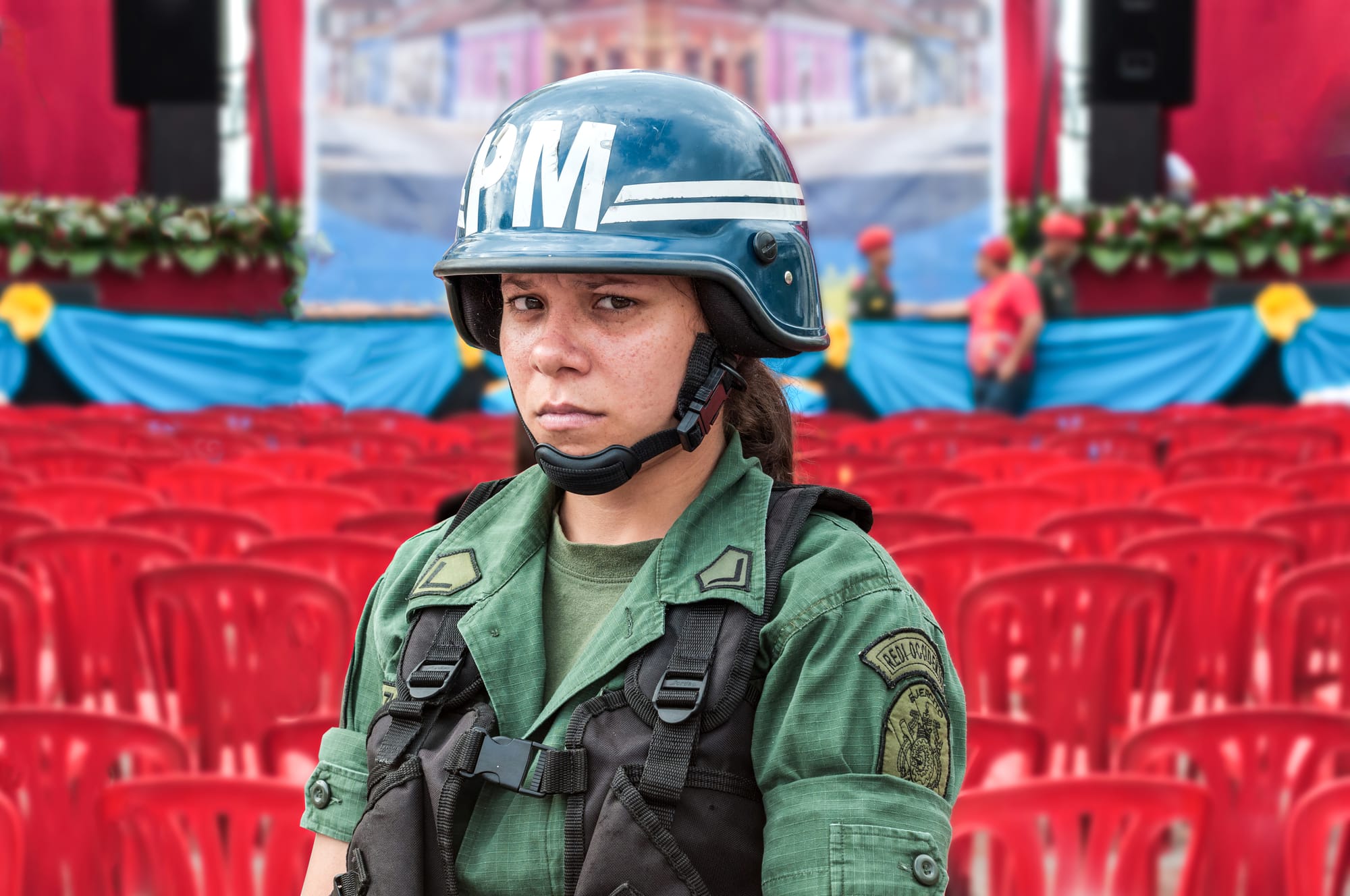 Military Police Woman in a presidential meeting. National Bolivarian Armed Forces and Revolutionary army, are used as personal protection for the president in public meetings. Red color in the meetings is traditionally associated with socialism in Venezuela, in this case, the red platform occupied the front of the Chiquinquirá Basilica.