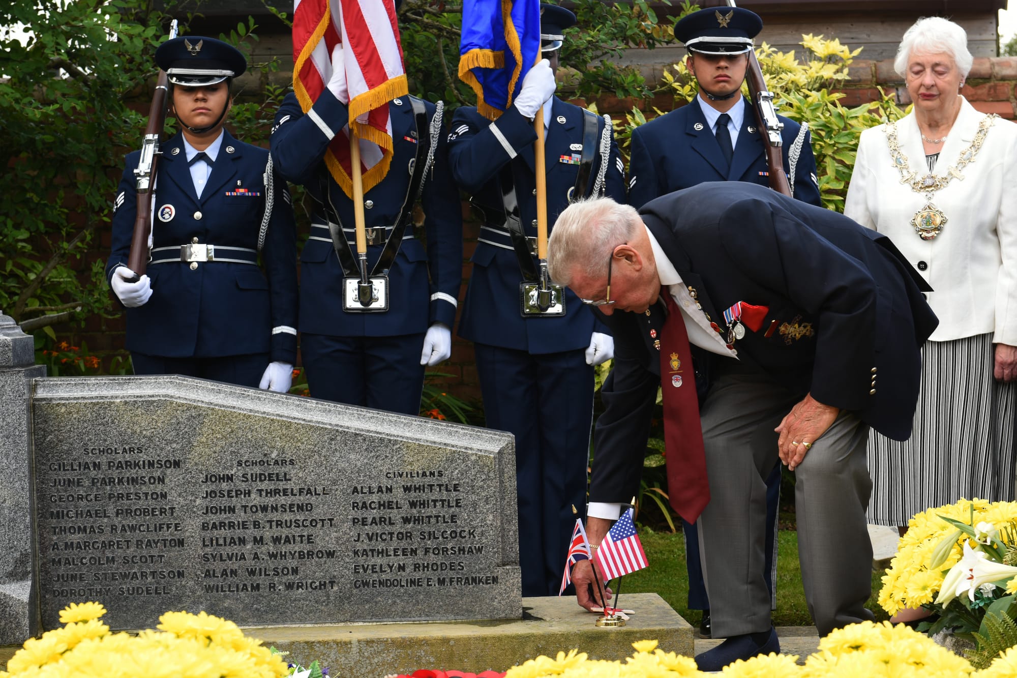 A family member of one of the casualties from the Freckleton Air Disaster adjusts the American and English flag during the flower-laying ceremony in Freckleton, England Aug. 23, 2019. On Aug. 23, 1944 a World War II U.S. Army Air Force B-24 Liberator Bomber crashed into a children's school claiming the lives of over 60 people, with over 30 of them being children. (U.S. Air Force photo by Senior Airman Christopher S. Sparks)