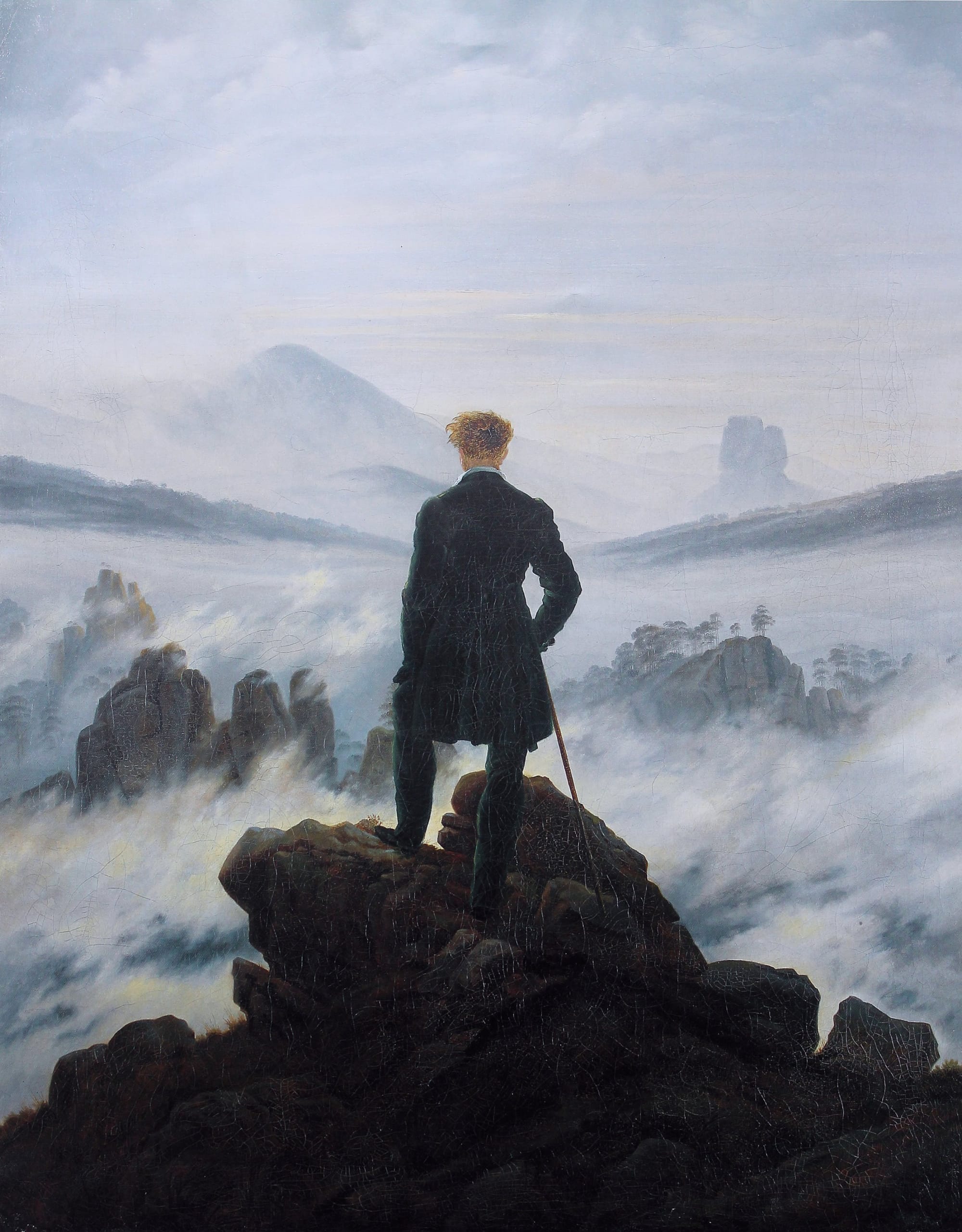 The hiker stands as a back figure in the center of the composition. He looks down on an almost impenetrable sea of fog in the midst of a rocky landscape - a metaphor for life as an ominous journey into the unknown.