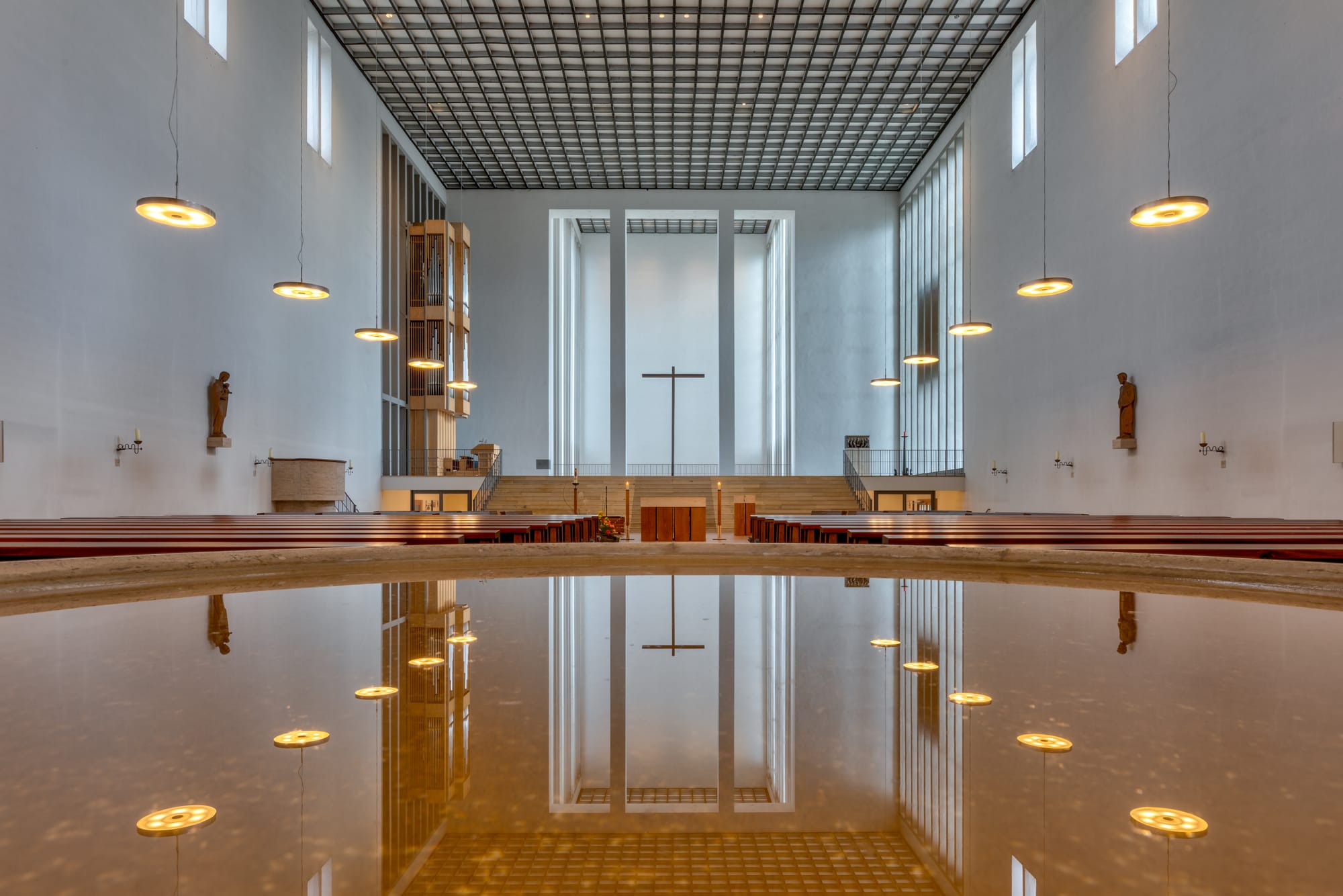 Interior view (with reflections in the stoup, a symbolic baptismal font) of the Holy Cross Church in Dülmen, North Rhine-Westphalia, GermanyThe Holy Cross Church is a Roman Catholic parish church that houses the tomb of the blessed mystic Anna Katharina Emmerick. It was built between 1936 and 1938 on Lüdinghauser Straße by church architect Dominikus Böhm as the second Catholic parish church and was consecrated on November 16, 1938, by the then Bishop of Münster, Clemens August Graf von Galen, as the last new church to be built in Germany before the Second World War. The church was partially destroyed by bombs on March 22, 1945. The building was rebuilt by 1953, although the baptistery was not rebuilt. The church was renovated and redesigned in the 1970s and 2000s.
