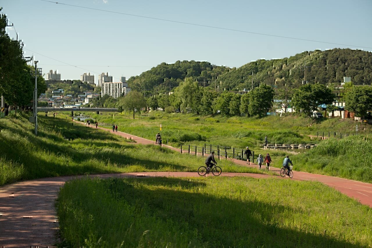 People walking and riding bicycles along a section of the restored Daejeoncheon river in the Seokgyo-dong neighborhood of Daejeon South Korea