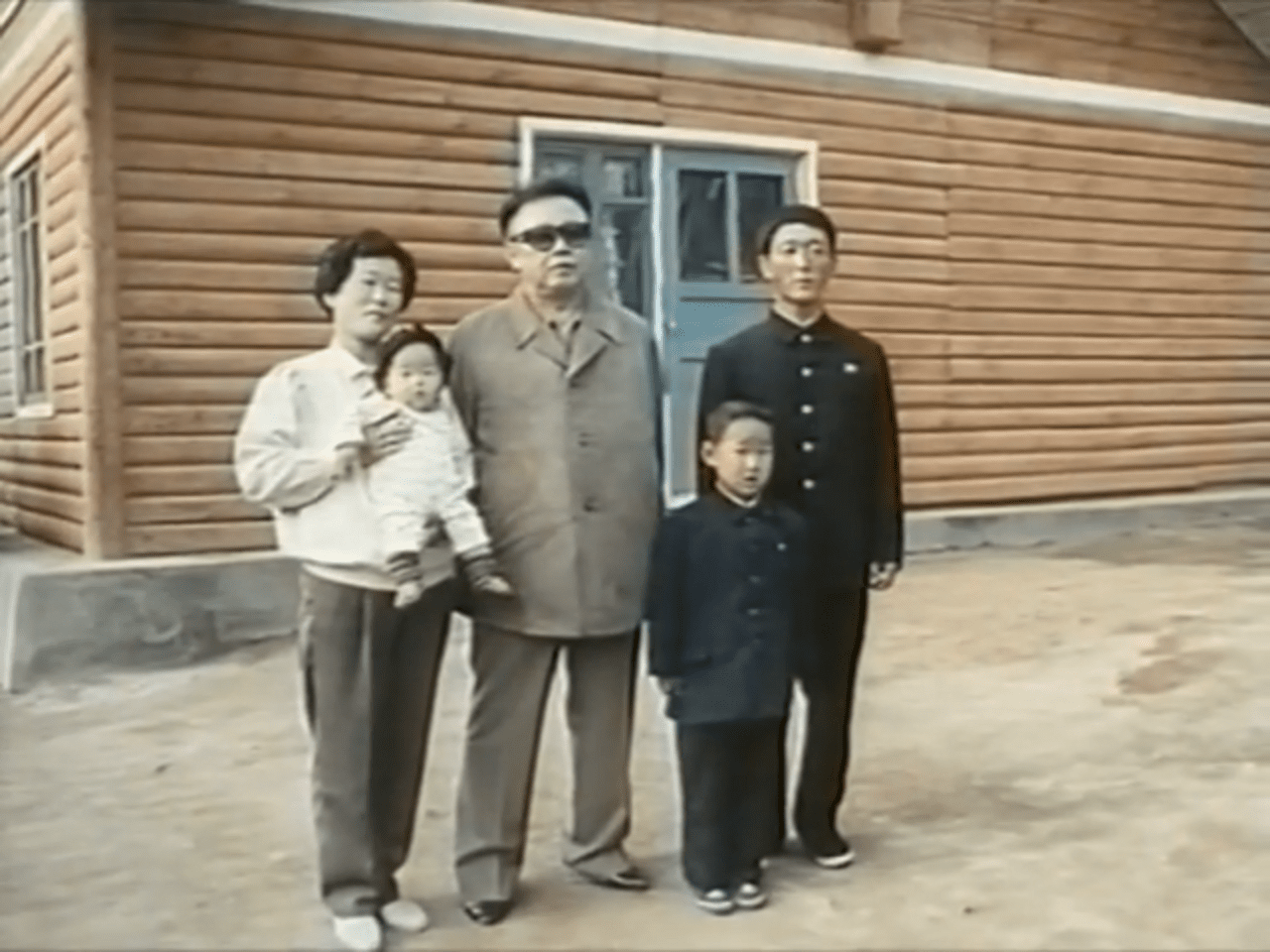 Kim Jong-il with a local family in a propaganda photo during the 1995-1999 famine.