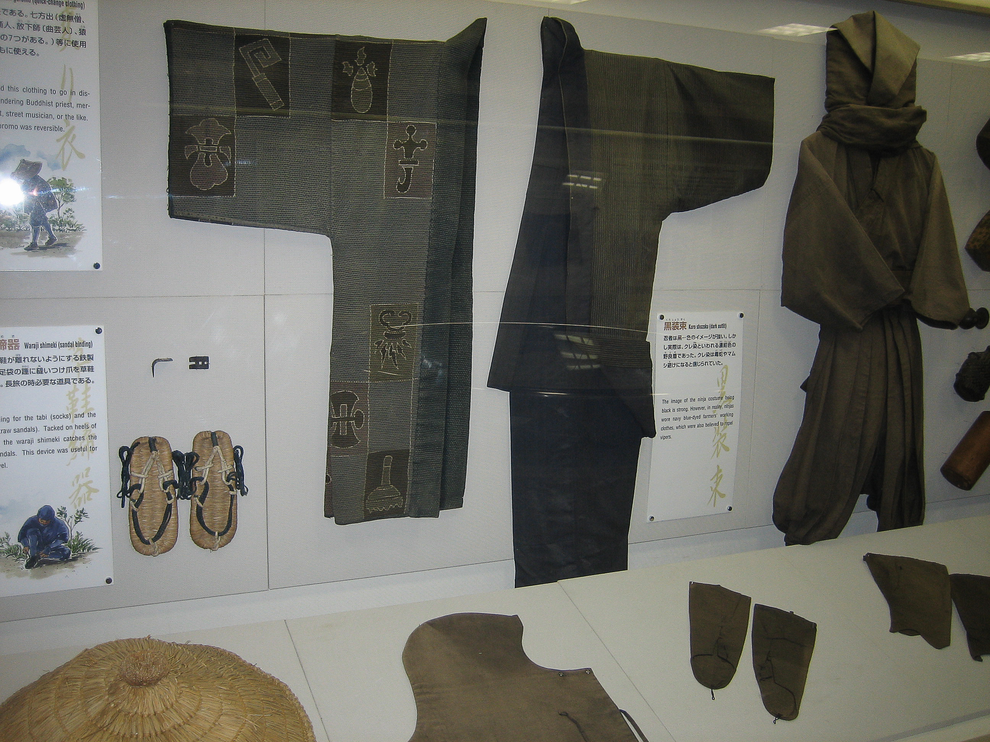 Kuro shozoku ninja costume at the Ninja Museum of Igaryu. "The image of the ninja costume being black is strong. However, in reality, ninjas wore navy blue-dyed farmers' working clothes, which were also believed to repel vipers." On the left side is waraji shimeki (sandal binding). Waraji are Japanese sandals.