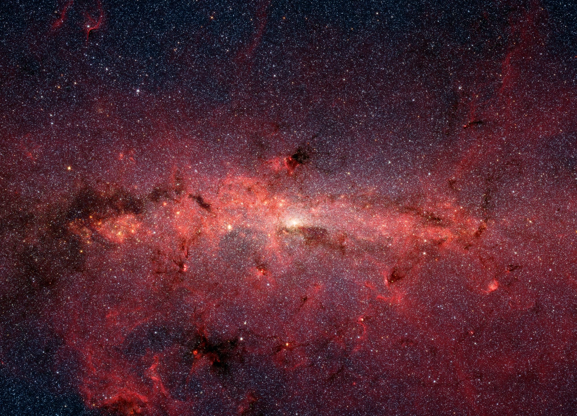 The center of our Milky Way galaxy is hidden from the prying eyes of optical telescopes by clouds of obscuring dust and gas. But in this stunning vista, the Spitzer Space Telescope's infrared cameras penetrate much of the dust, revealing the stars of the crowded galactic center region. The upcoming James Webb Space Telescope will offer a much-improved infrared view, teasing out fainter stars and sharper details.
The center of our galaxy is a crowded place: A black hole weighing 4 million times as much as our Sun is surrounded by millions of stars whipping around it at breakneck speeds. This extreme environment is bathed in intense ultraviolet light and X-ray radiation. Yet much of this activity is hidden from our view, obscured by vast swaths of interstellar dust.
NASA’s James Webb Space Telescope is designed to view the universe in infrared light, which is invisible to the human eye, but is very important for looking at astronomical objects hidden by dust. After its launch, Webb will gather infrared light that has penetrated the dusty veil, revealing the galactic center in unprecedented detail.
