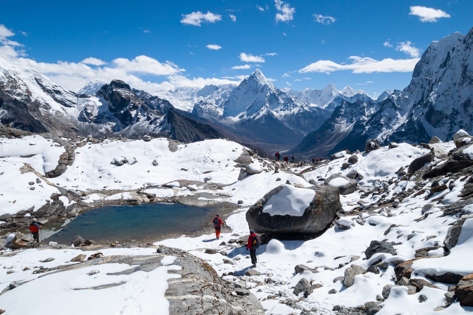Mountains in snow. Mountain lake. View to the east on descending from Cho La Pass into Chola Valley, 5,200 metres (17,100 ft) a. s. l. Glacial lake, rocks covered with snow, Ama Dablam (6,810 metres (22,343 ft)) and other Himalayan peaks to the south of the Great Himalayan Range in Mahalangur Himal. Nepal, Himalayas.