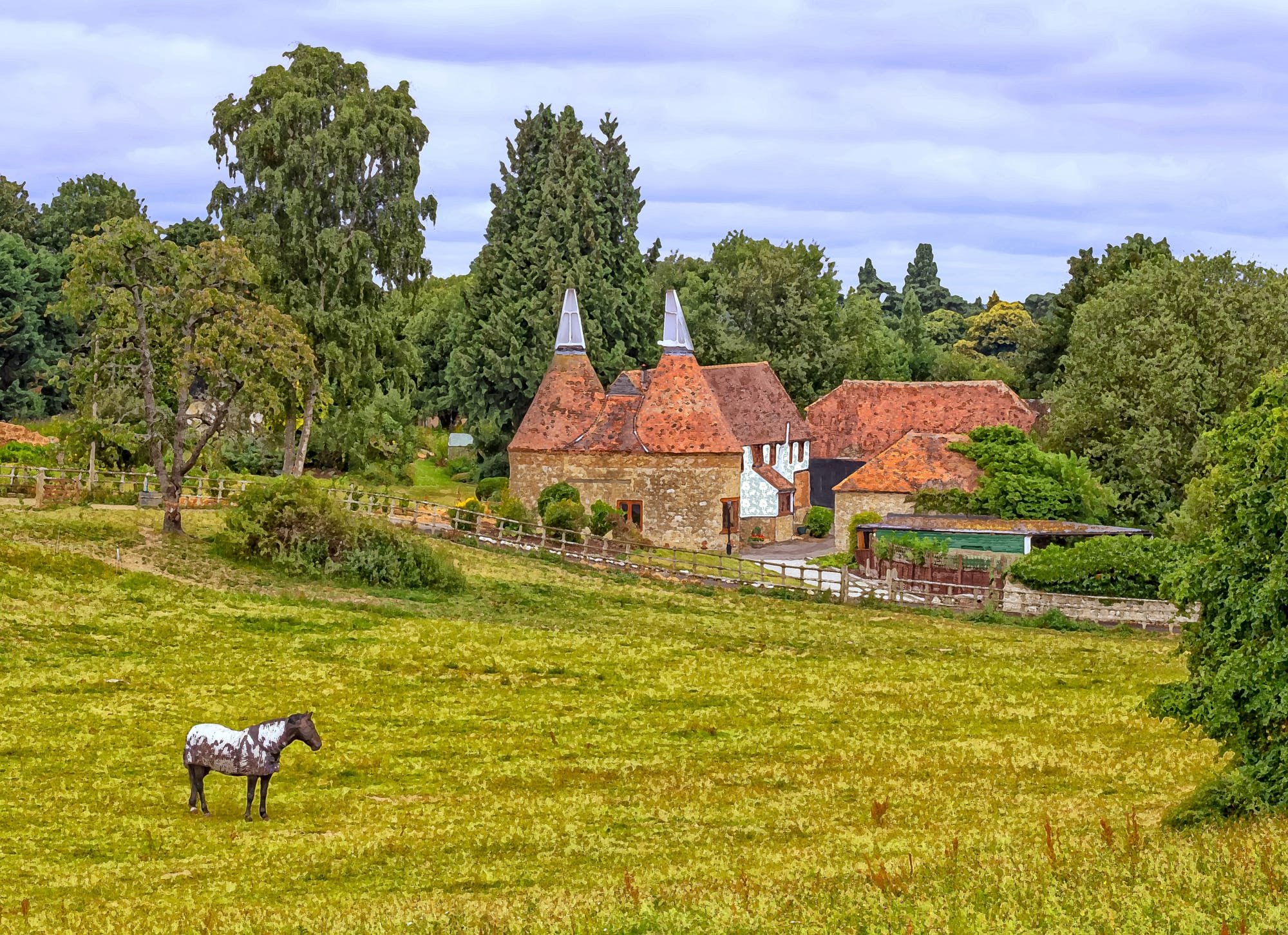 An oast, oast house or hop kiln is a building designed for kilning (drying) hops as part of the brewing process. They can be found in most hop-growing (and former hop-growing) areas and are often good examples of vernacular architecture. Many redundant oasts have been converted into houses. The names oast and oast house are used interchangeably in Kent and Sussex. 
They consist of a rectangular one or two storey building (the "stowage") and one or more kilns in which the hops were spread out to be dried by hot air rising from a wood or charcoal fire below. The drying floors were thin and perforated to permit the heat to pass through and escape through a cowl in the roof which turned with the wind. The freshly picked hops from the fields were raked in to dry and then raked out to cool before being bagged up and sent to the brewery. The Kentish dialect word kell was sometimes used for kilns ("The oast has three kells") and sometimes to mean the oast itself ("Take this lunchbox to your father, he's working in the kell"). The word oast itself also means "kiln".
Oasts are generally associated with Kent, and the oasthouse is a symbol associated with the county. 

en.m.wikipedia.org/wiki/Oast_house