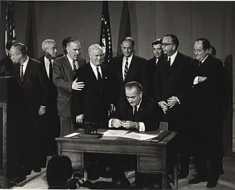 This photograph was taken by an NIH photographer of President Lyndon Johnson signing a bill with Vice-President Humphrey standing to the far right.  The bill content is unknown but can be assumed to be a bill concerned with health care legislation.