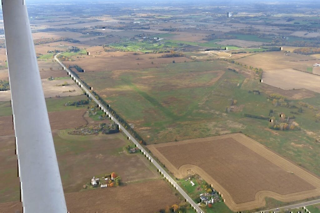 The World War II Royal Canadian Air Force airfield at Burtch, Ontario, Canada, as it was in November 2016.   The airfield was built in 1941 as part of the British Commonwealth Air Training Plan.   This view, from about 1,000' above ground level, has the camera pointing to southwest.
The triangle pattern of the runways is clearly visible, with the intersection of runway 25 (on the right) and 20 (left) at the centre of the frame.   Runway 30 is at the top of frame.
The hangar and camp area is marked by lines of trees at the right of frame.

This airfield was restored to farmland by the Government of Ontario between 2009 and 2015, and then given to a First Nations band in settlement of a land claim. The photograph was taken from the left front seat of Cessna 172 C-GBSL, from a height of 300 metres above ground level.  Pilot in command, in the right seat, was Aaron Webb. The white "pole" on the left side of the frame is the left wing strut.