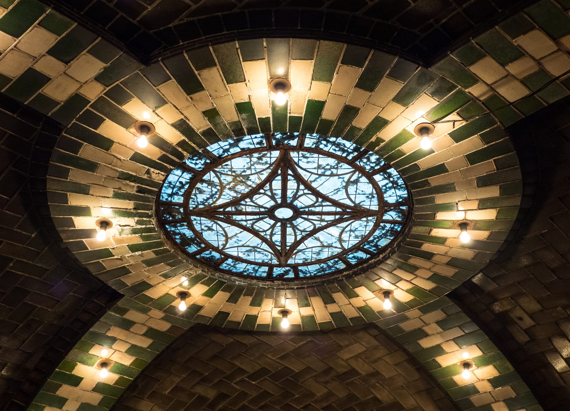 The defunct City Hall subway station in New York City, closed since 1945. The station has several skylights. Most of them are built into the arches above the platform. This is the sole circular skylight above the mezzanine. Visible from above in the middle of the City Hall parking lot.