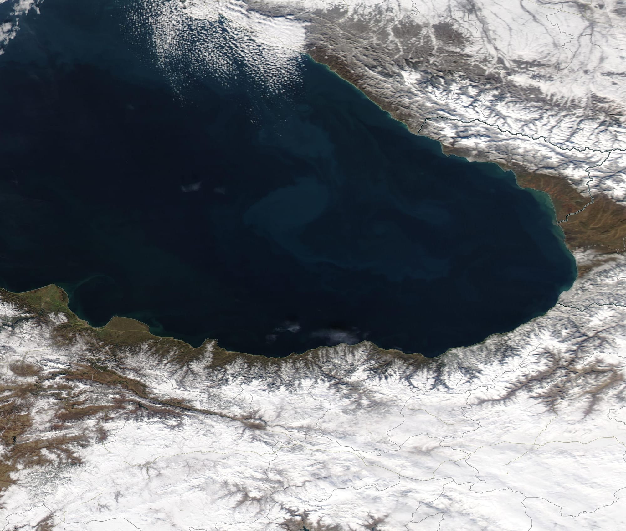 Bright white snow framed the dark waters of the Black Sea in late January 2021. The Moderate Resolution Imaging Spectroradiometer (MODIS) on board NASA’s Aqua satellite acquired a true-color image of the winter’s scene on January 21.
Heavy snow drapes over Turkey’s Pontic Mountains south of the Black Sea while the Great Caucasus Mountains wear a wintery mantle along the northeast shore. In the lower elevations the land appears tan, illustrating the senescence of winter vegetation. While the plants on land have dried with the winter’s chill, plant-like organisms have blossomed in the deep blue waters of the Black Sea, creating swirls of green so large they can be seen from space. Known as phytoplankton, the microscopic organisms live in these waters year-round in relatively small numbers. When conditions are right—correct nutrients, sunlight, and water temperature—they reproduce explosively creating large floating blooms. While summer is the best time for phytoplankton blooms in the Black Sea, they may occur any time of the year.
