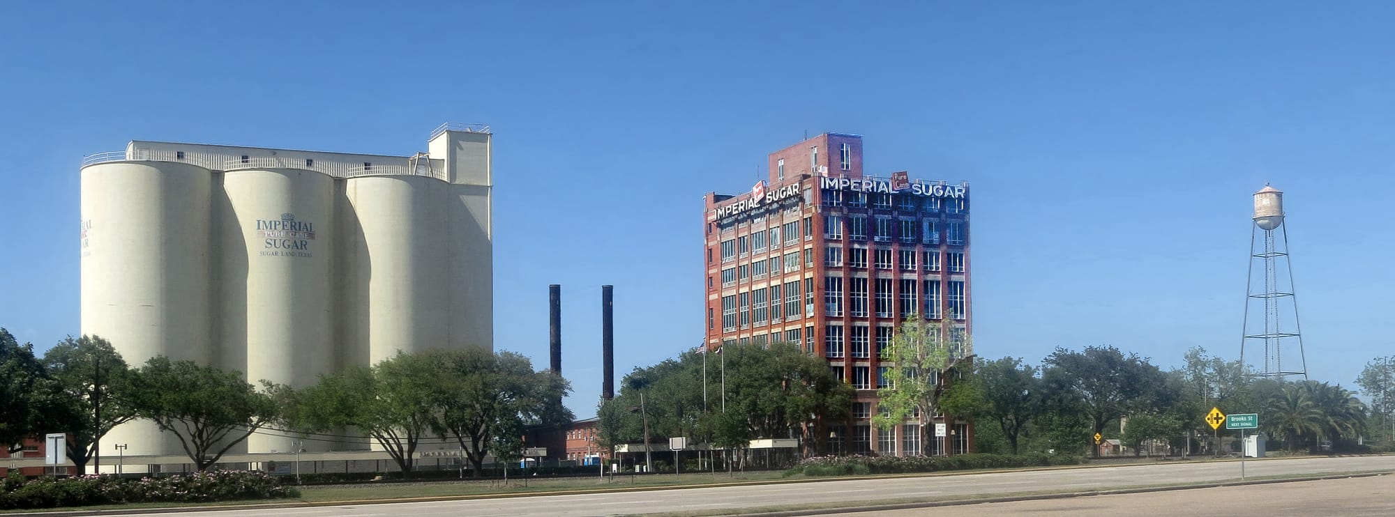 The Sugar Land Refinery.
Stephen F. Austin's colonists brought sugar cane to Fort Bend County in the 1820s. The Sugar Land area was once part of Oakland Plantation, where Nathaniel and Matthew Williams planted sugar cane about 1840. They began processing the cane in 1843 using a horse-powered mill and open-air cooking kettles. In 1853 the plantation and mill were purchased by William J. Kyle and Benjamin F. Terry. They improved the mill and promoted a railroad for the area, which they named Sugar Land. Terry later helped organize the famed Confederate cavalry unit, Terry's Texas Rangers, and was killed in the Civil War. After the war, the operation was sold to Edward H. Cunningham, who expanded the sugar mill into a refinery. W. T. Eldridge and Galveston businessman I. H. Kempner, Sr. bought the refinery in 1907. They began importing raw sugar to operate the refinery year-round because local cane was available only seasonally and in decreasing quantities in the early 1900s. Named by Kempner for the Imperial Hotel in New York City, the Imperial Sugar Company and the City of Sugar Land have grown steadily. During the 1970s, the Imperial Sugar Company produced more than three million pounds of refined cane sugar daily.