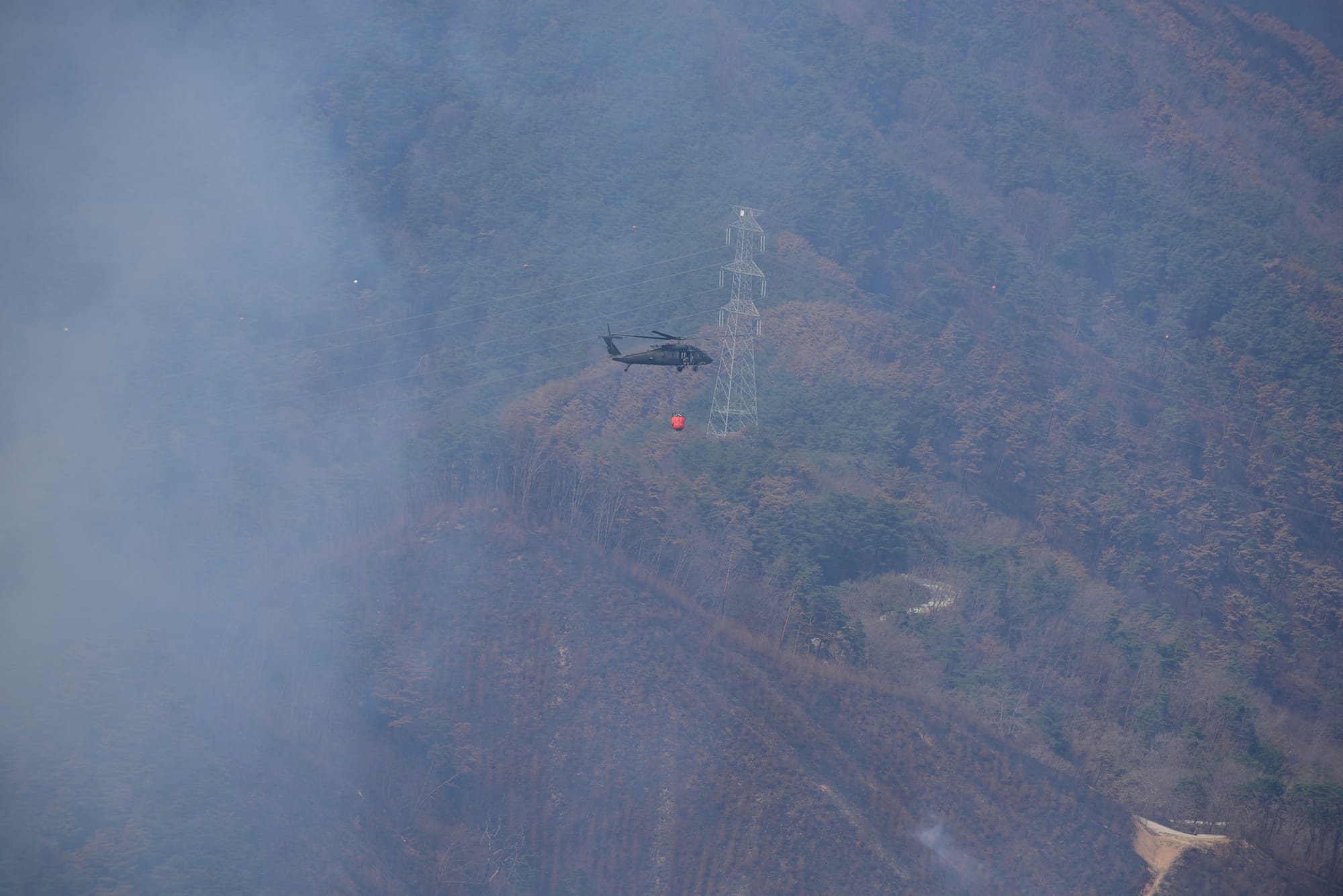U.S. Forces Korea is assisting efforts to contain wildfires in southeastern regions of the Republic of Korea. In coordination with the U.S. Embassy in Seoul, ROK Joint Chiefs of Staff and Combined Forces Command, USFK has deployed UH-60 Black Hawk helicopters equipped with Bambi Buckets to support aerial water drop operations. Personnel from the 2nd Combat Aviation Brigade, including pilots and crew chiefs, are actively supporting the mission, with additional assets on standby if needed. (U.S. Army photo by Sgt. Alexander Knight)