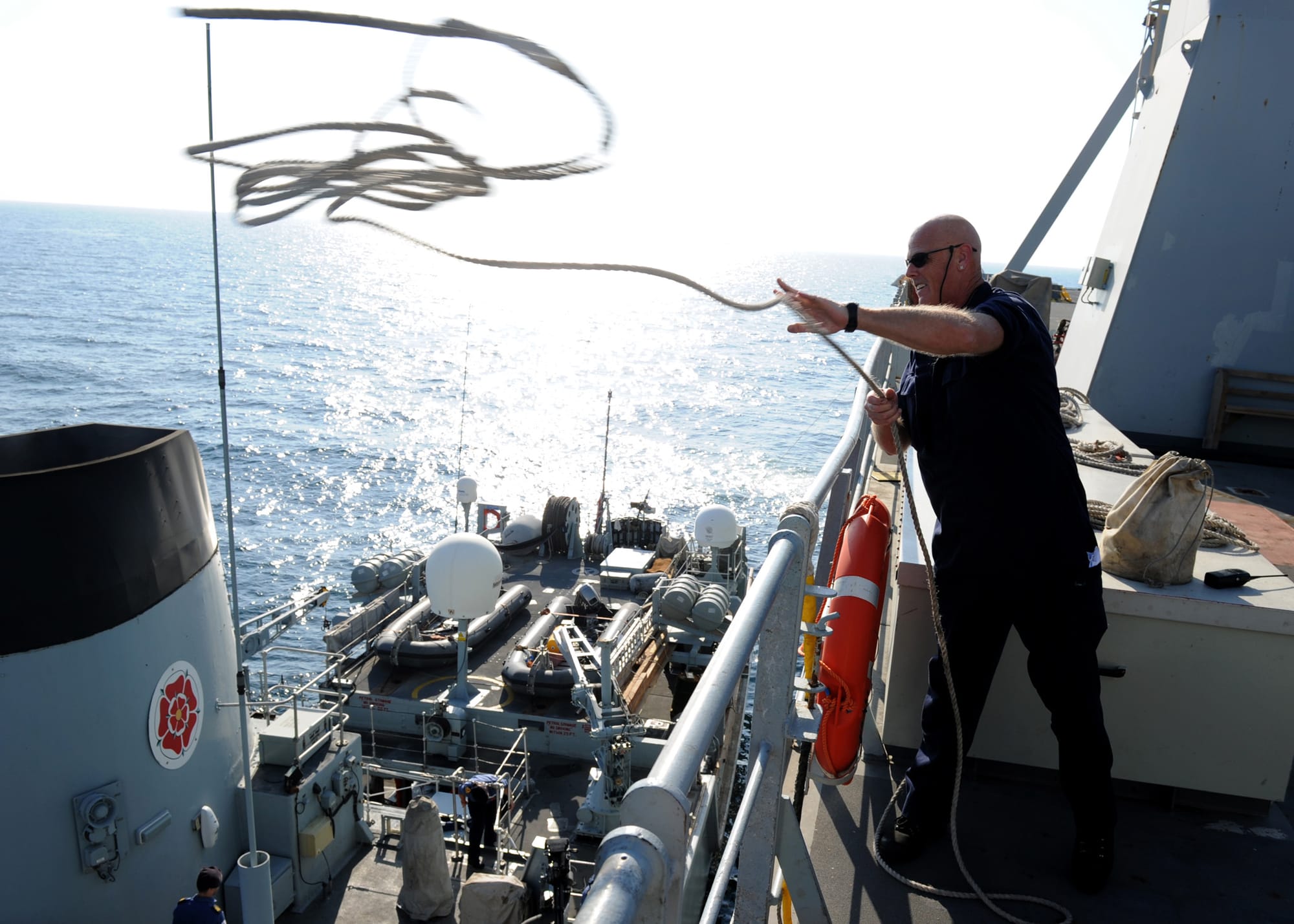 STRAITS OF HORMUZ  (Nov. 13, 2010) Ray Delbridge, assigned to the Royal Fleet Auxiliary landing ship Lyme Bay (L3007), throws a line to the Royal Navy mine countermeasure ship HMS Chiddenfold (M 37) before rafting during a joint exercise. Chiddenfold and Lyme Bay are part of Combined Task Force (CTF) 151 deployed supporting maritime security operations in the U.S. 5th Fleet area of responsibility. (U.S. Navy photo by Mass Communication Specialist 1st Class Joshua Lee Kelsey/Released)