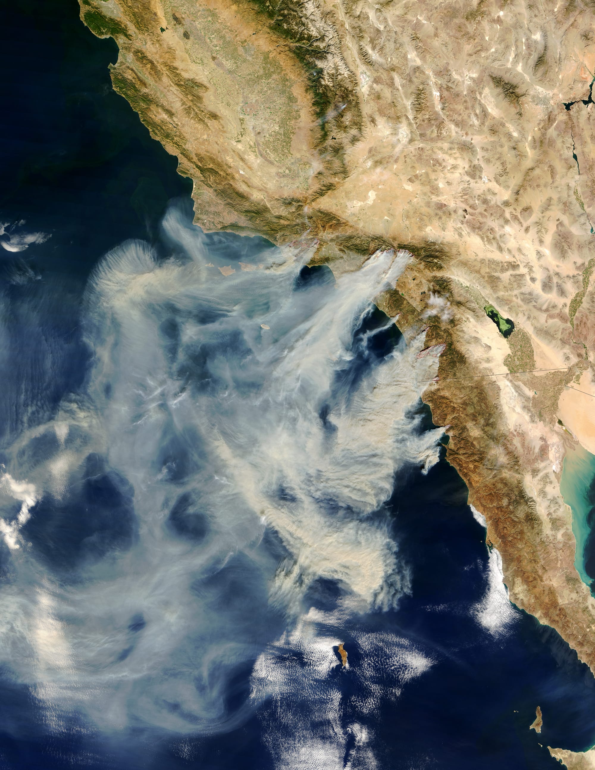 Several massive wildfires were raging across southern California over the weekend of October 25, 2003. Whipped by the hot, dry Santa Ana winds that blow toward the coast from interior deserts, at least one fire grew 10,000 acres in just 6 hours. The modis.gsfc.nasa.gov Moderate Resolution Imaging Spectroradiometer (MODIS) on the terra.nasa.gov Terra satellite captured this image of the fires and clouds of smoke spreading over the region on October 26, 2003. The red polygons indicate precisely where the fires are burning, or have recently burned. (Compare this scene with one captured by the MODIS instrument aboard the Aqua satellite just earthobservatory.nasa.gov/NaturalHazards/natural_hazards_v2.php3?img_id=11800 one day before .) In and around Simi Valley are the Piru, Verdale, and Simi Incident Fires; the next cluster -- to the right of Los Angeles -- is the Grand Prix (left) and Old (right) Fires. Closer to San Diego is the Roblar 2 Fire burning in the Camp Pendleton marine base. The Paradise Fire is encroaching on Escondido. The smoke of the massive Cedar Fire is completely obscuring the coastal city of San Diego. Finally, at the California-Mexico border is the Otay Fire. At least 13 people have lost their lives because of these fires, several of which appear to have been caused by carelessness and arson. Thousands have been evacuated across the region and hundreds of homes have been destroyed.
NASA Identifier: California.A2003299.1840